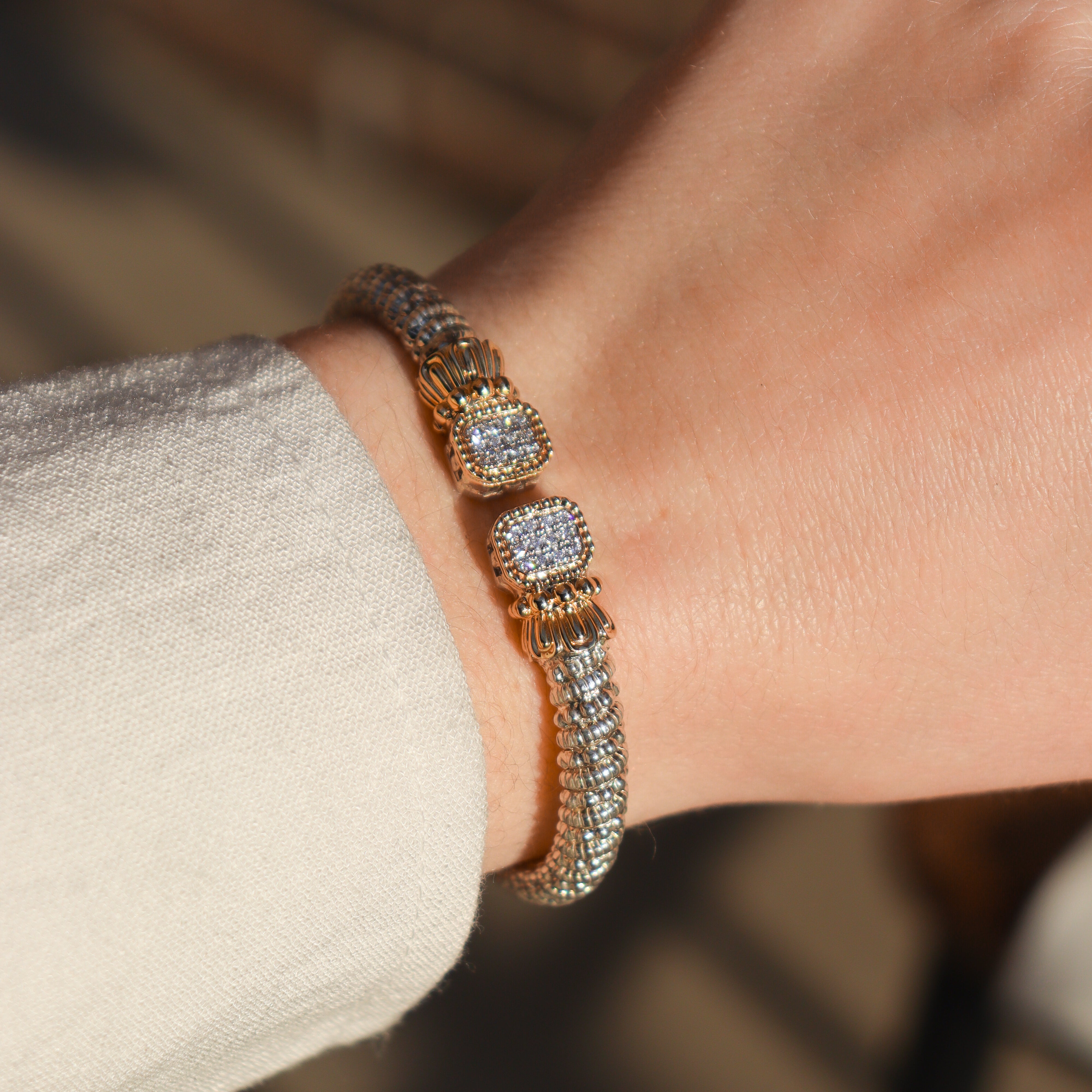 Designer Alwand Vahan cuff bracelet with diamonds on a wrist against a neutral background