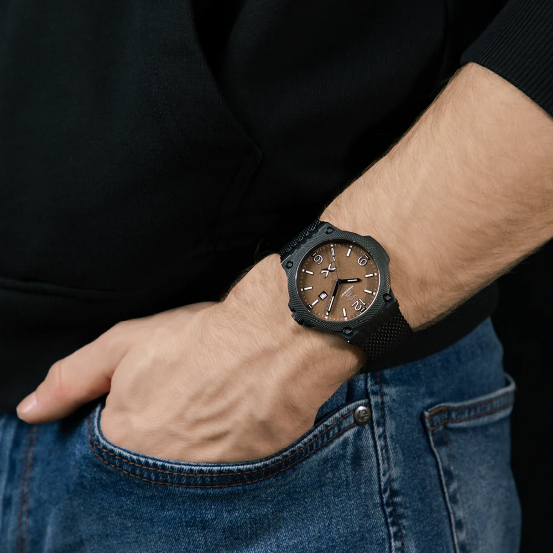 Person wearing a black wristwatch with a brown face on a black background