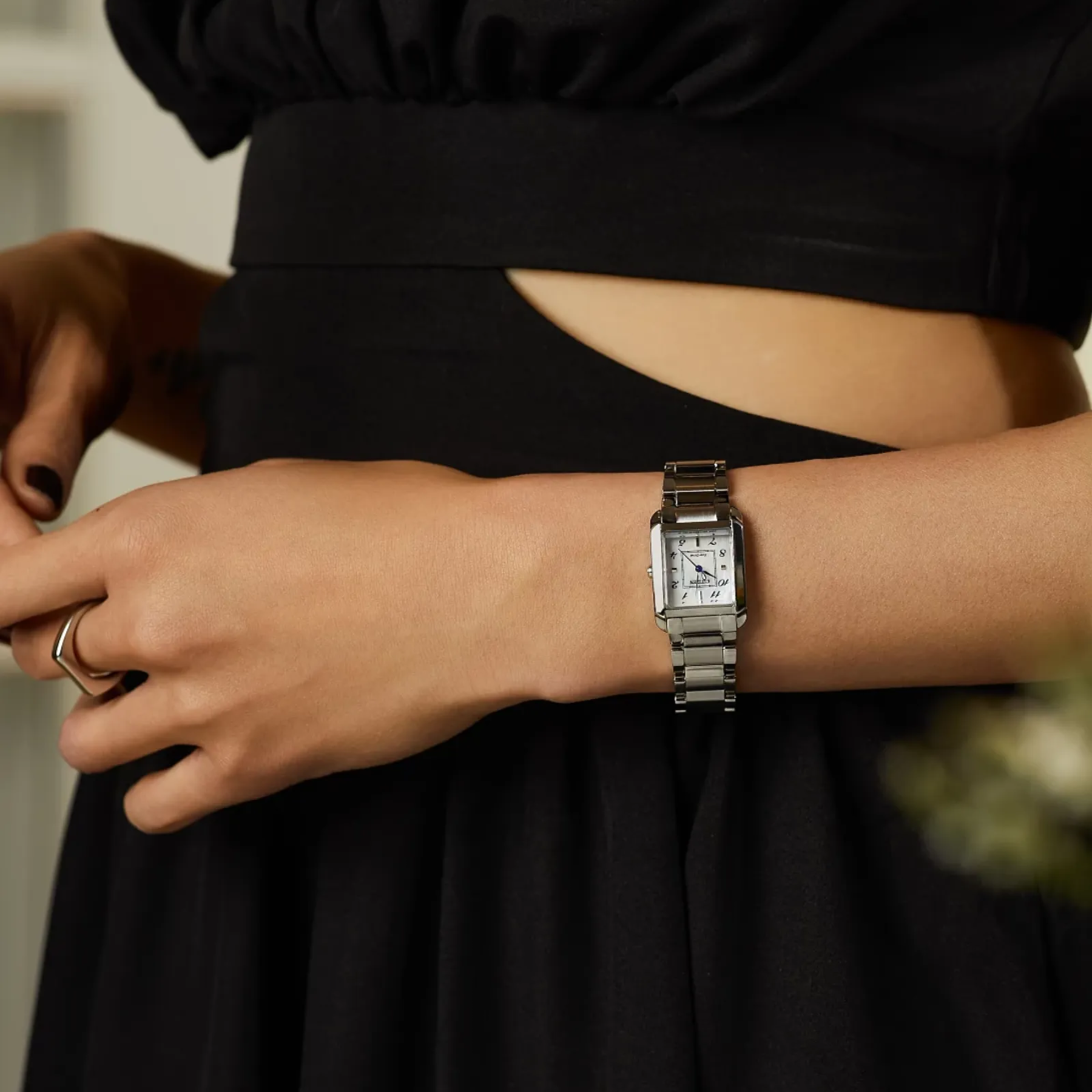 Person wearing a silver watch on a blurred background