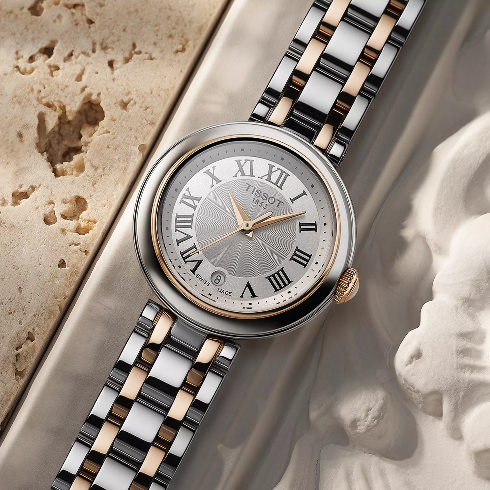 Luxury Tissot watch with a two-tone metal strap on a classical sculpture background