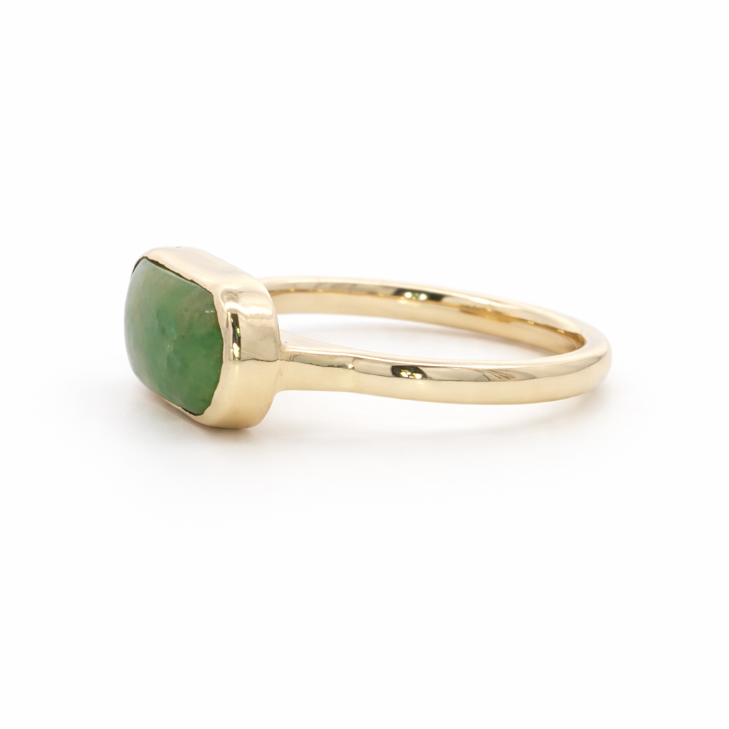 Gold ring with a green stone on a white background