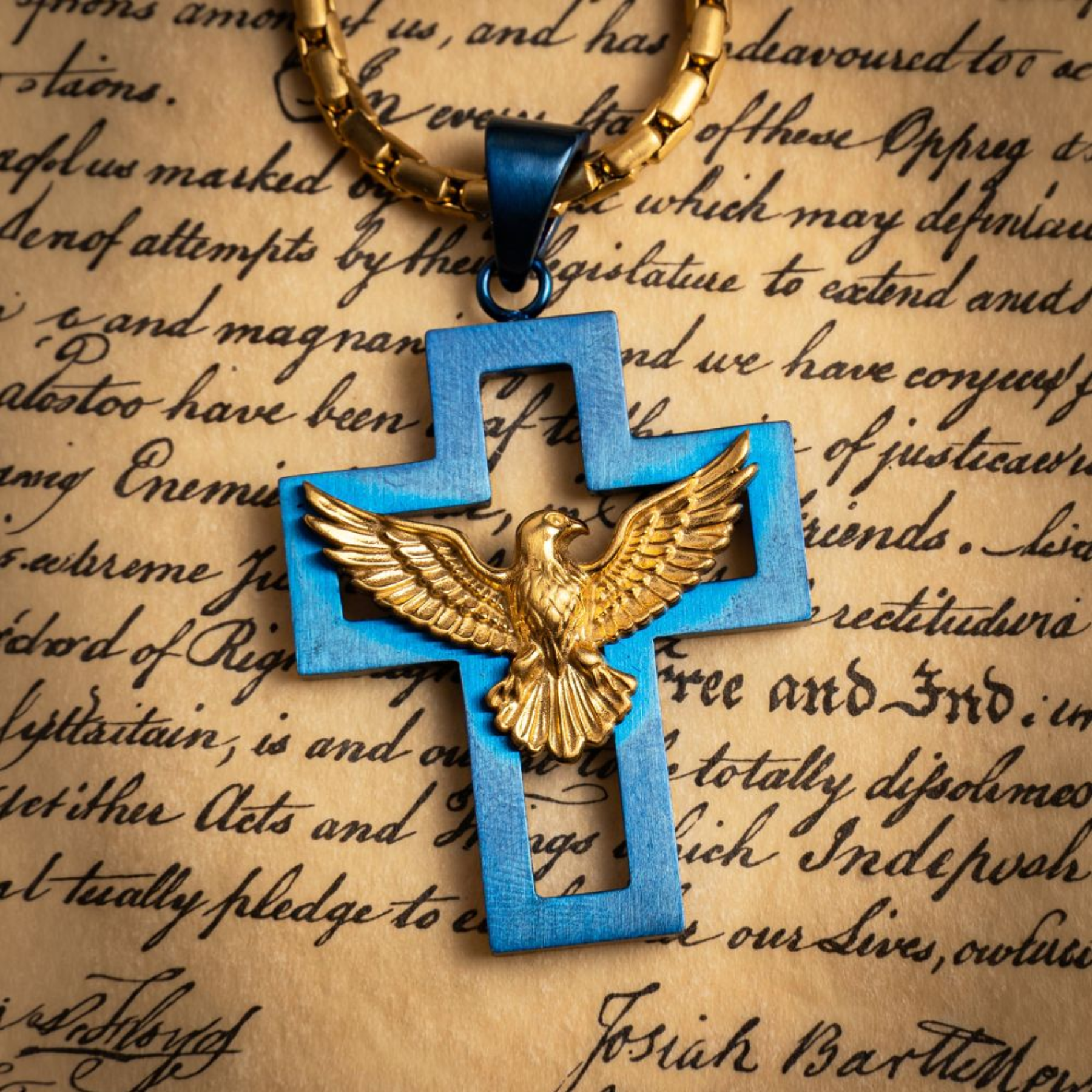 Blue cross pendant with gold eagle design on a textured paper background