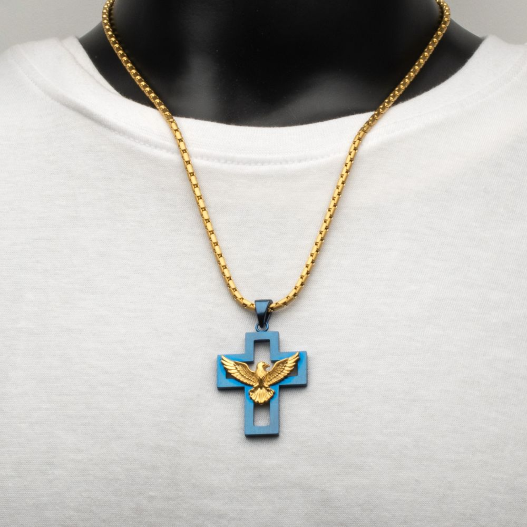 Gold and blue cross pendant necklace on a mannequin with a white shirt