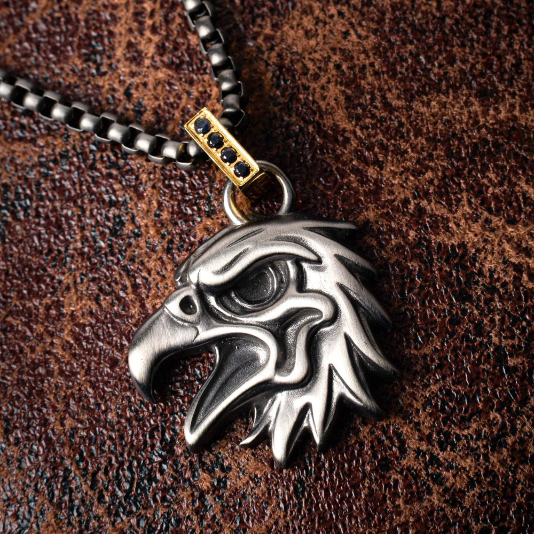 Silver eagle pendant on a chain against a brown leather background
