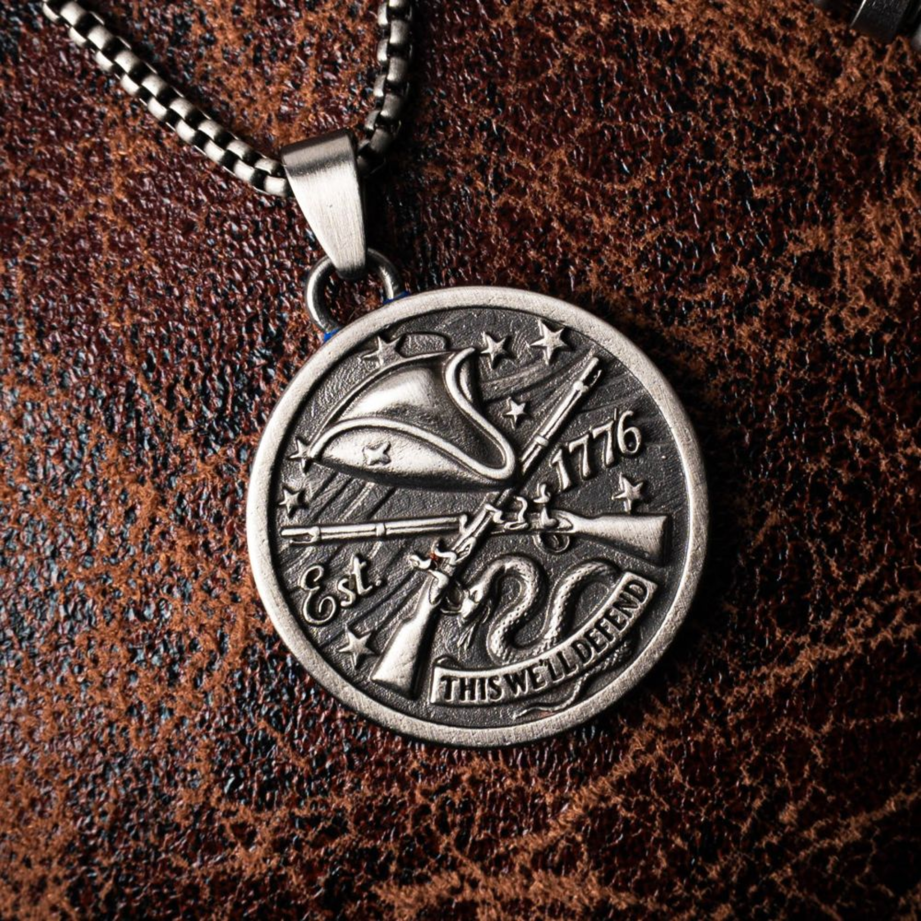 Silver necklace with a detailed pendant on a brown leather background