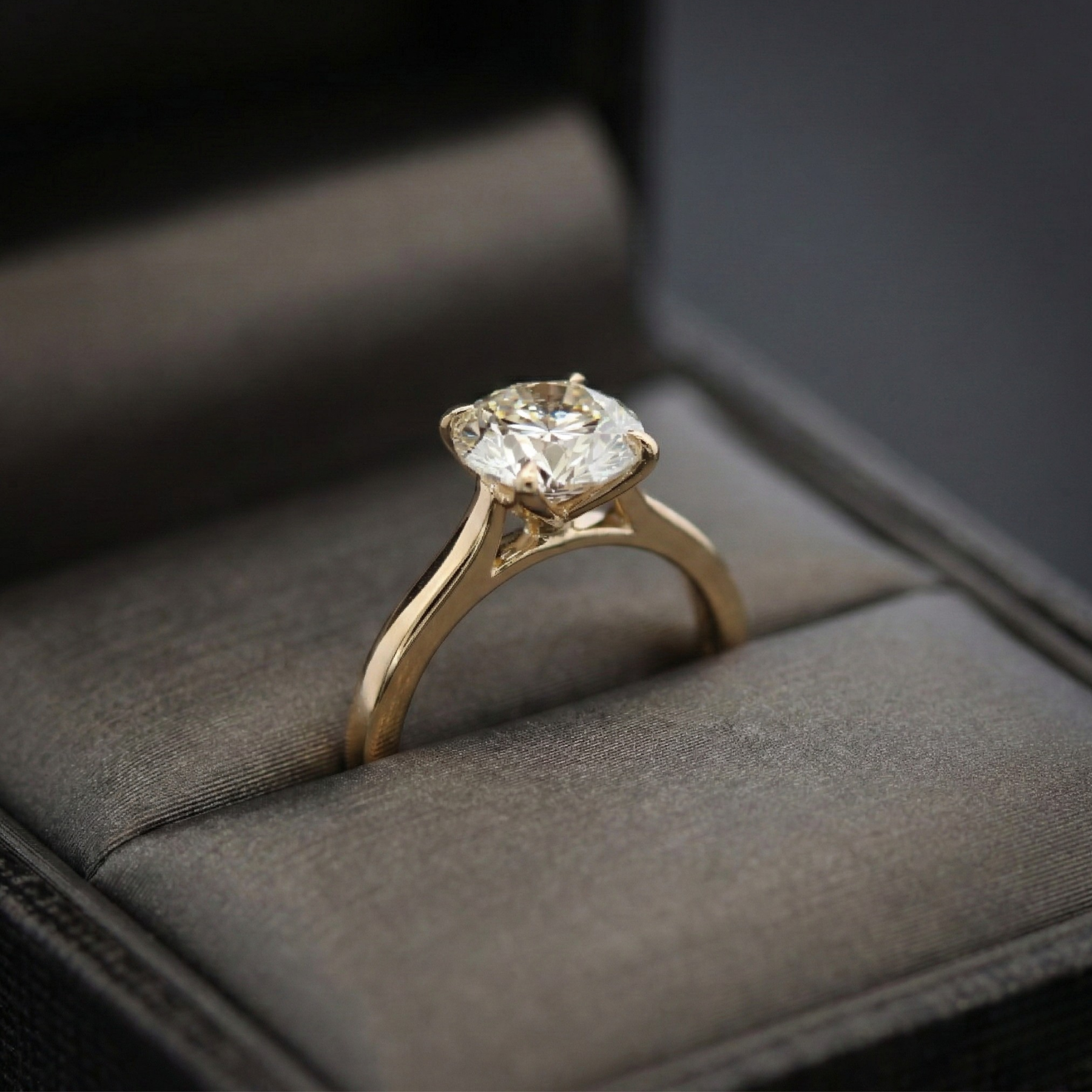 Gold ring with a diamond in a gray jewelry box