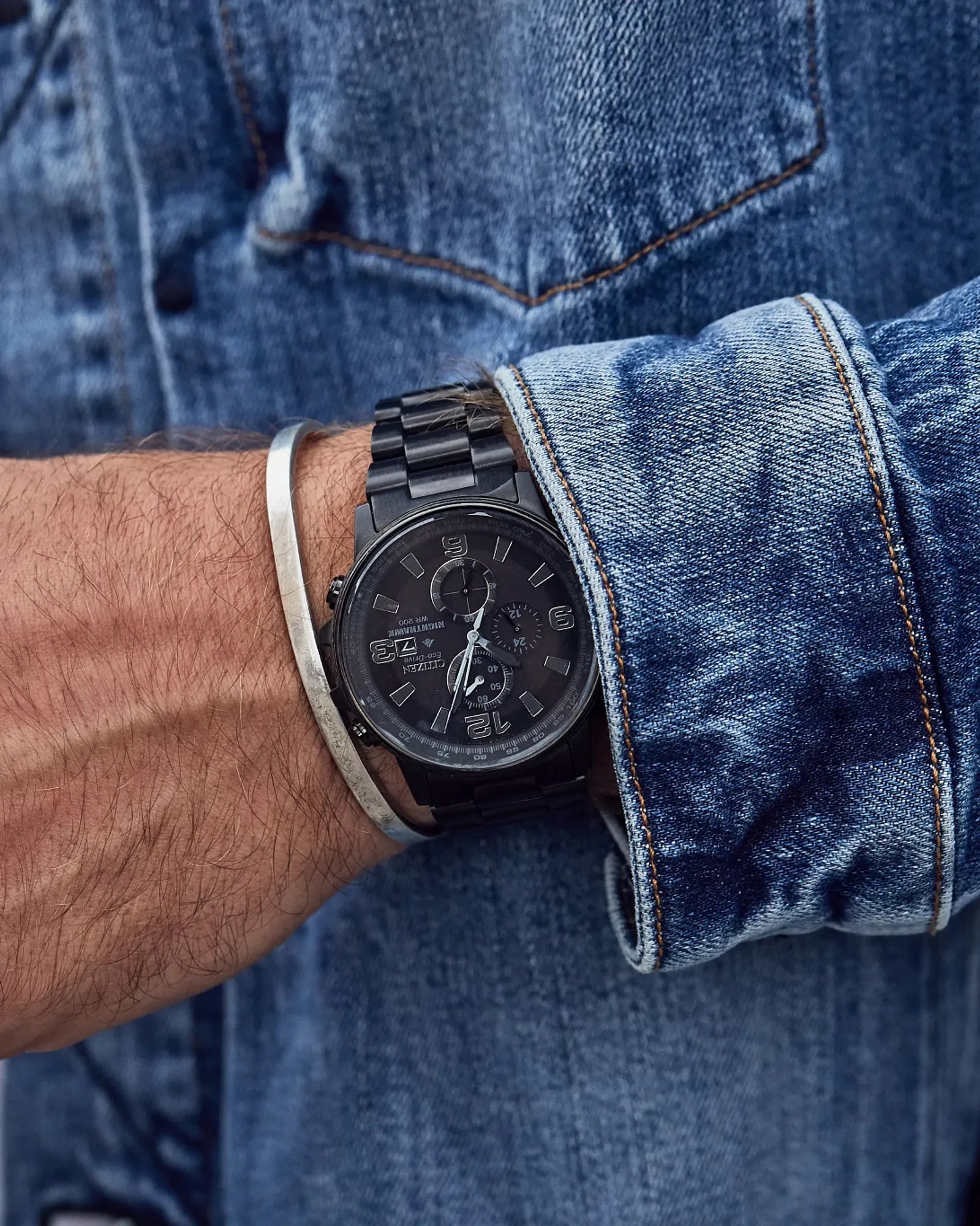 Person wearing a black watch with a denim jacket