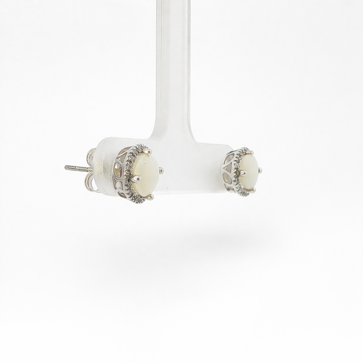 Pair of earrings on a white stand against a white background