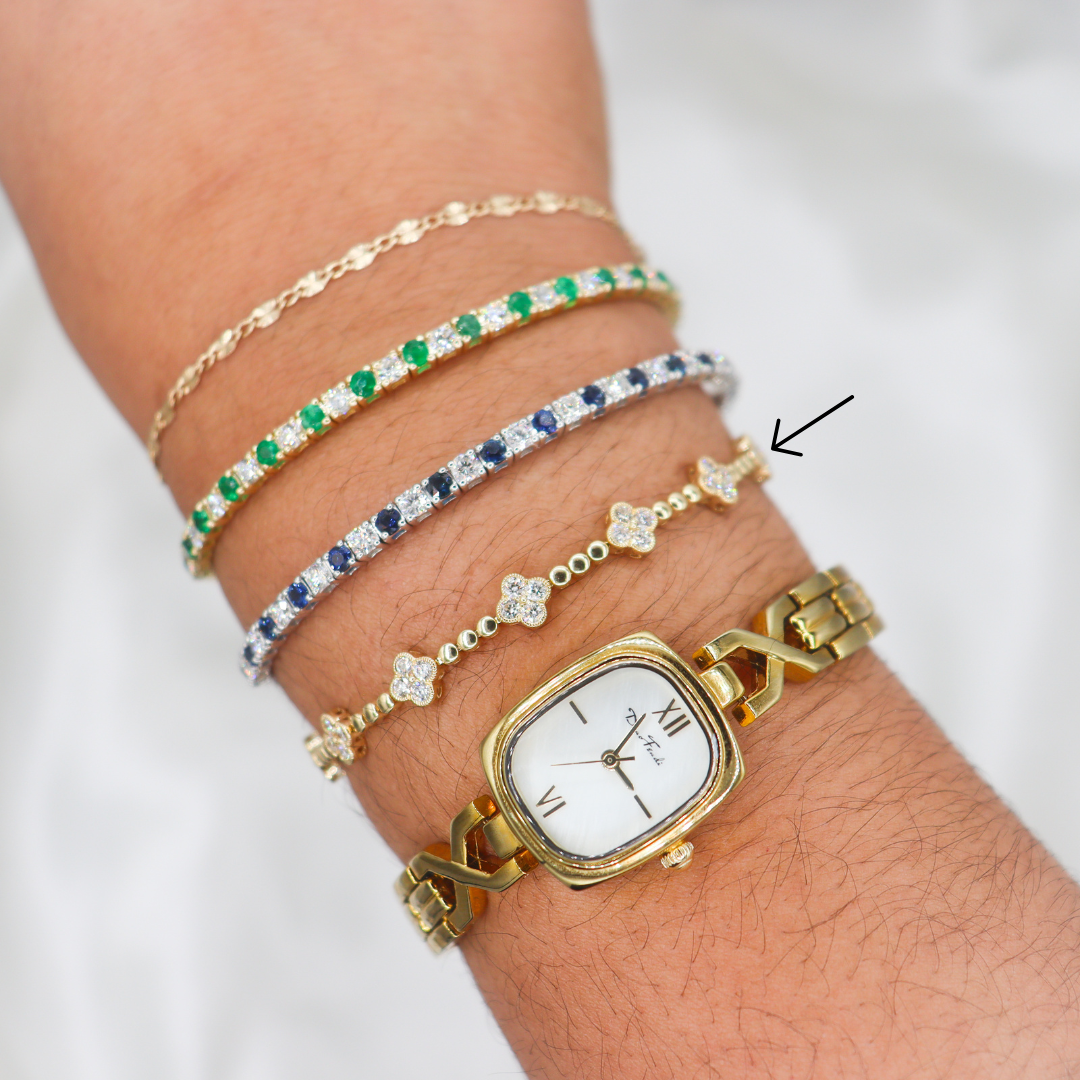 14K Yellow Gold Diamond Clover Station Tennis Bracelet stacked with other bracelets on a wrist