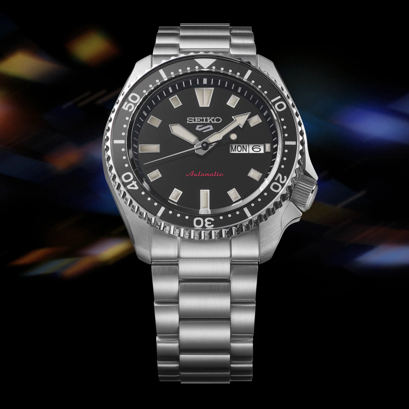 Seiko watch with black dial and silver metal strap on a dark background