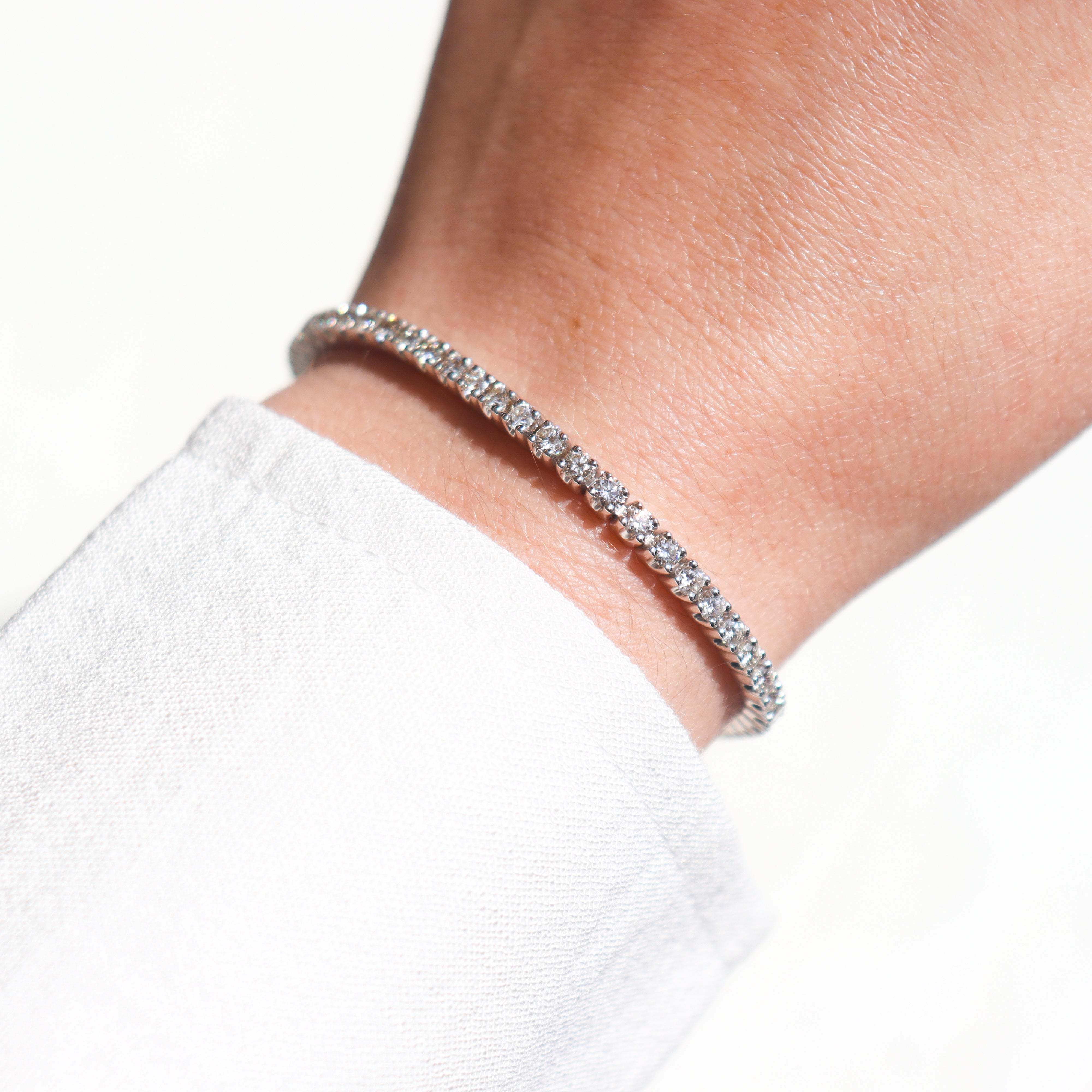 A 14K White Gold 4 carat total weight natural diamond tennis bracelet on a model's wrist.