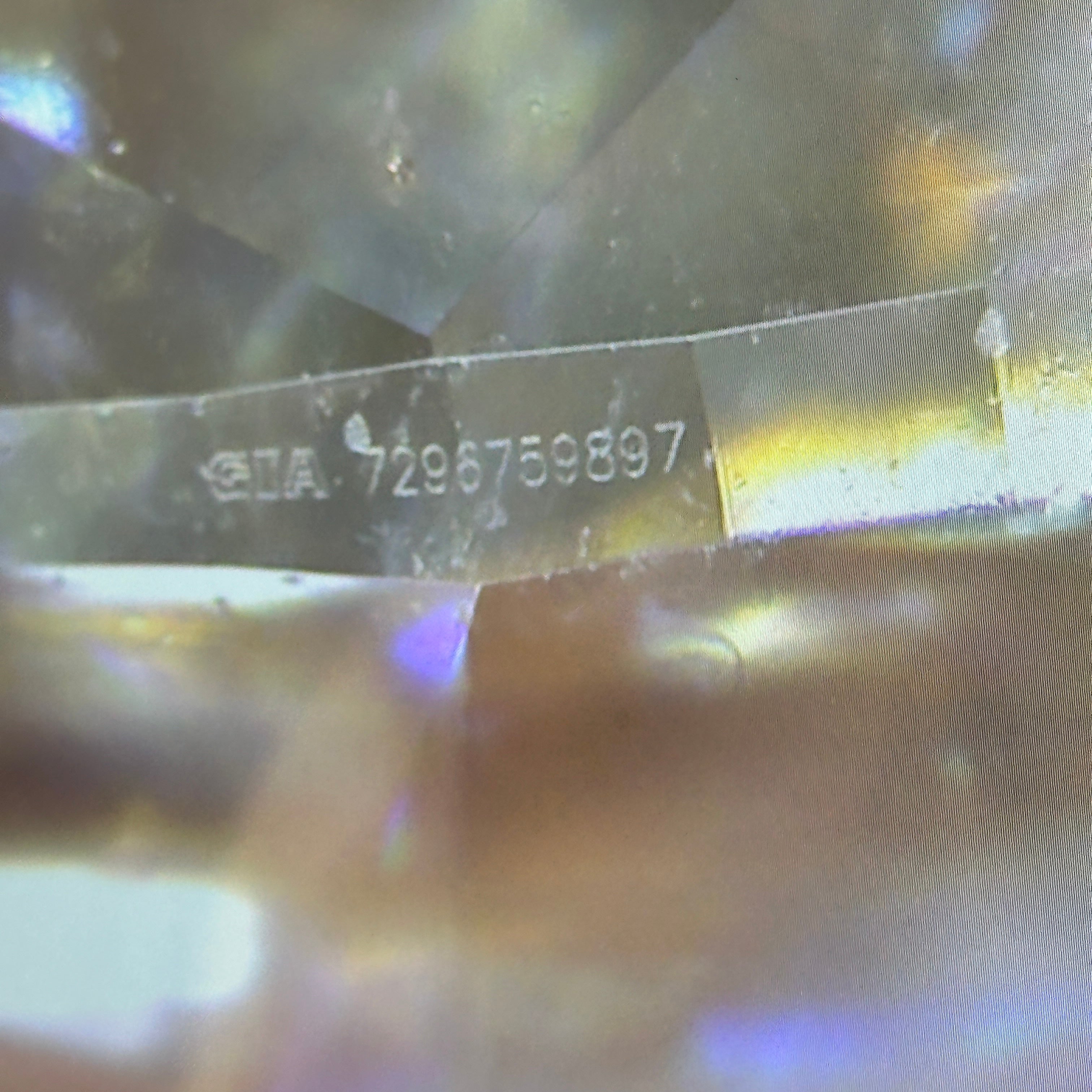 Close-up of a diamond with 'GIA' and a serial number engraved on it.