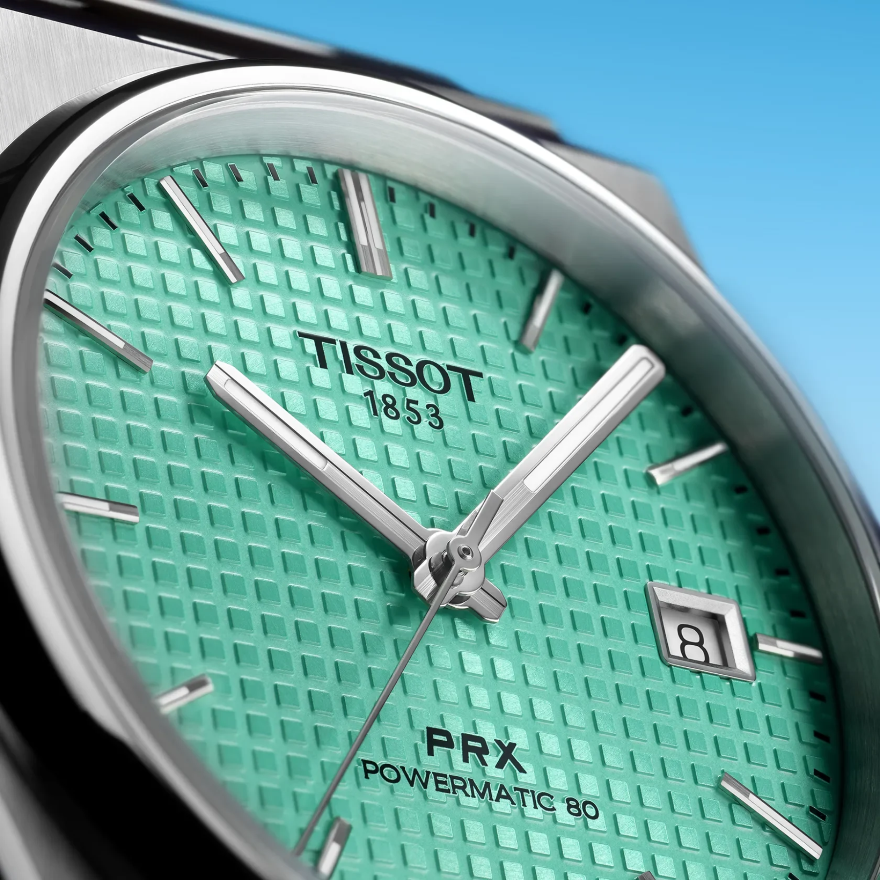 Tissot watch with green face and silver accents on a blue background