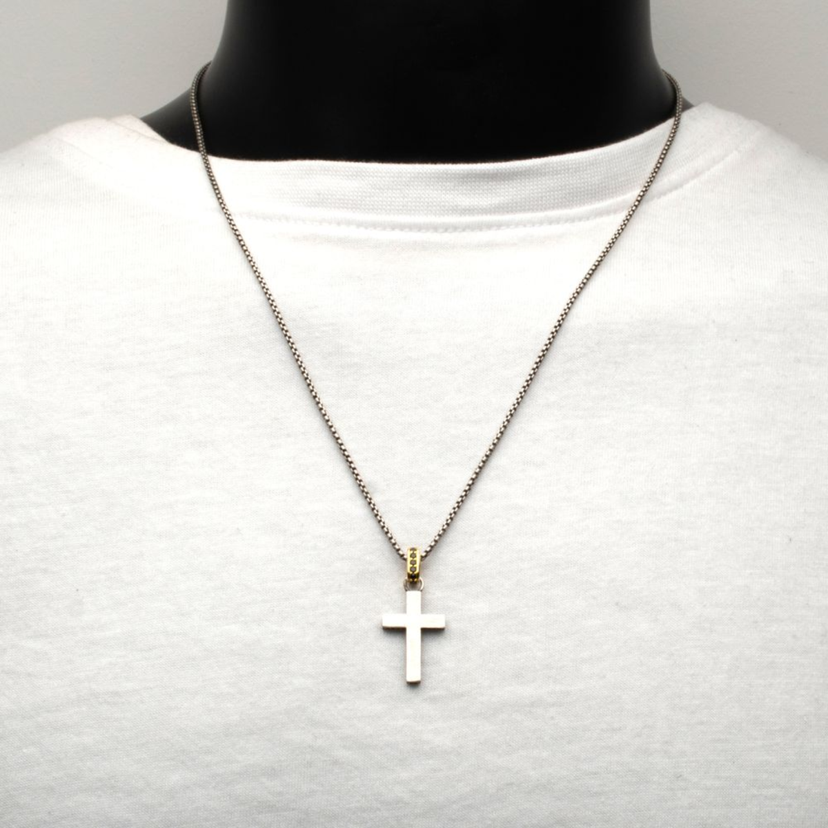 Cross pendant necklace on a mannequin with a plain background