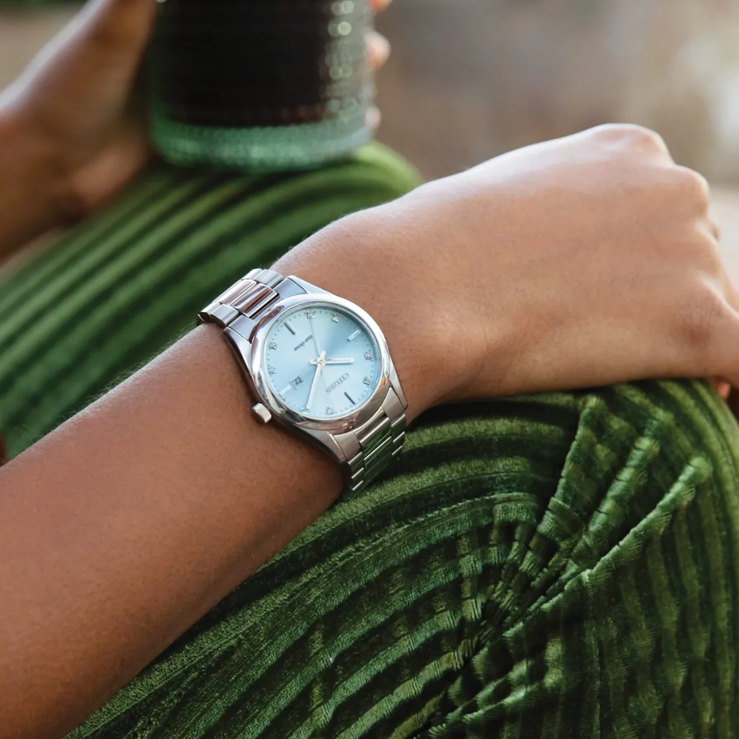 Front view of CITIZEN Sport Luxury Blue Dial Women's Watch on a a model's wrist, resting on her green velvet pants.
