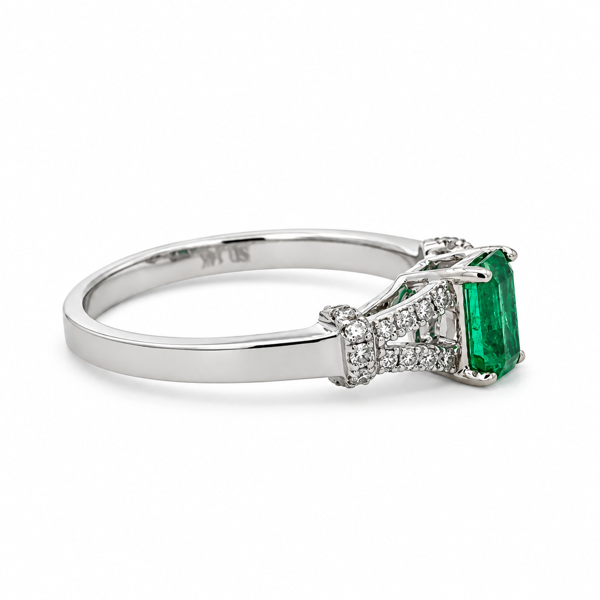 Side view of a 14K white gold ring with a 0.45 CT. emerald and 0.15 CTW. diamond accents on a white background