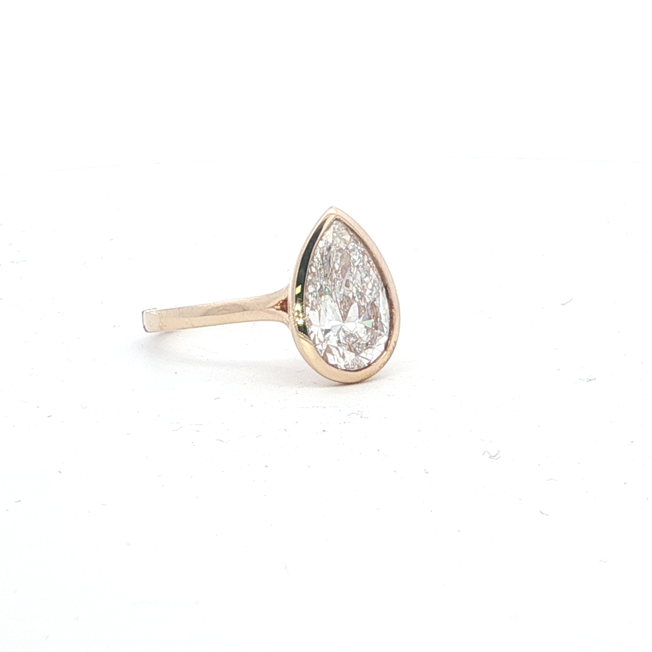 Rose gold teardrop-shaped diamond earring on a white background