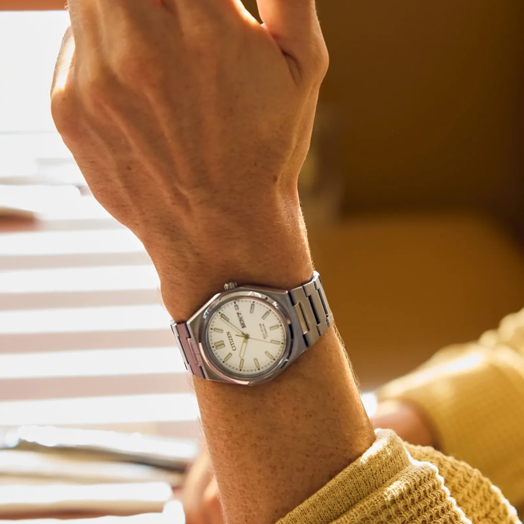 Close-up of a wrist wearing a silver watch with a blurred background