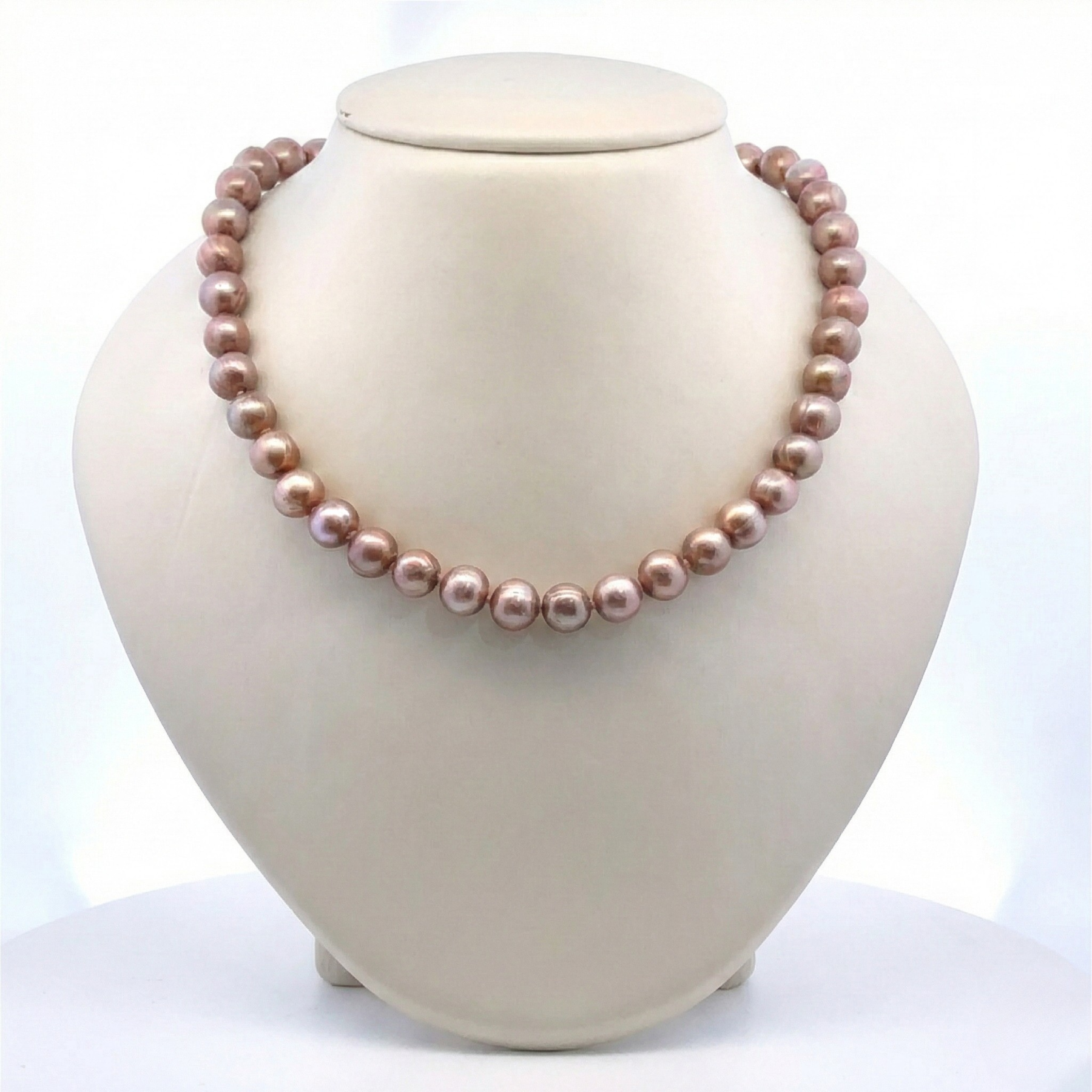 Pearl necklace on a white mannequin bust with a plain background