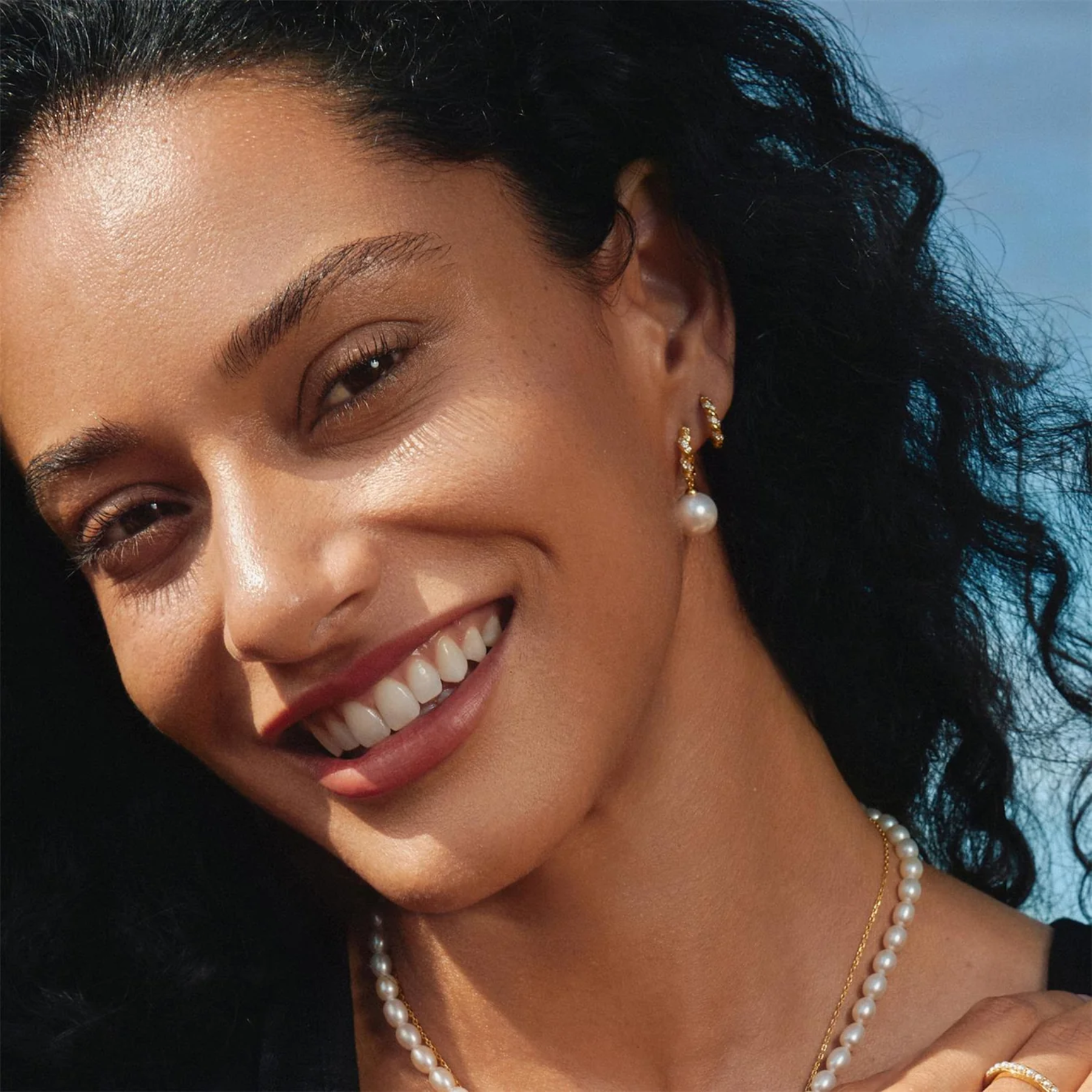 Woman wearing pearl earrings and necklace with a blurred background