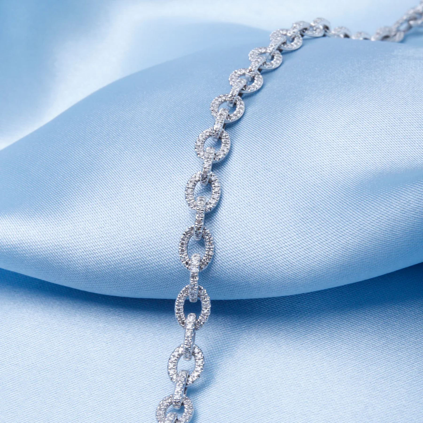 Silver bracelet on a light blue satin background