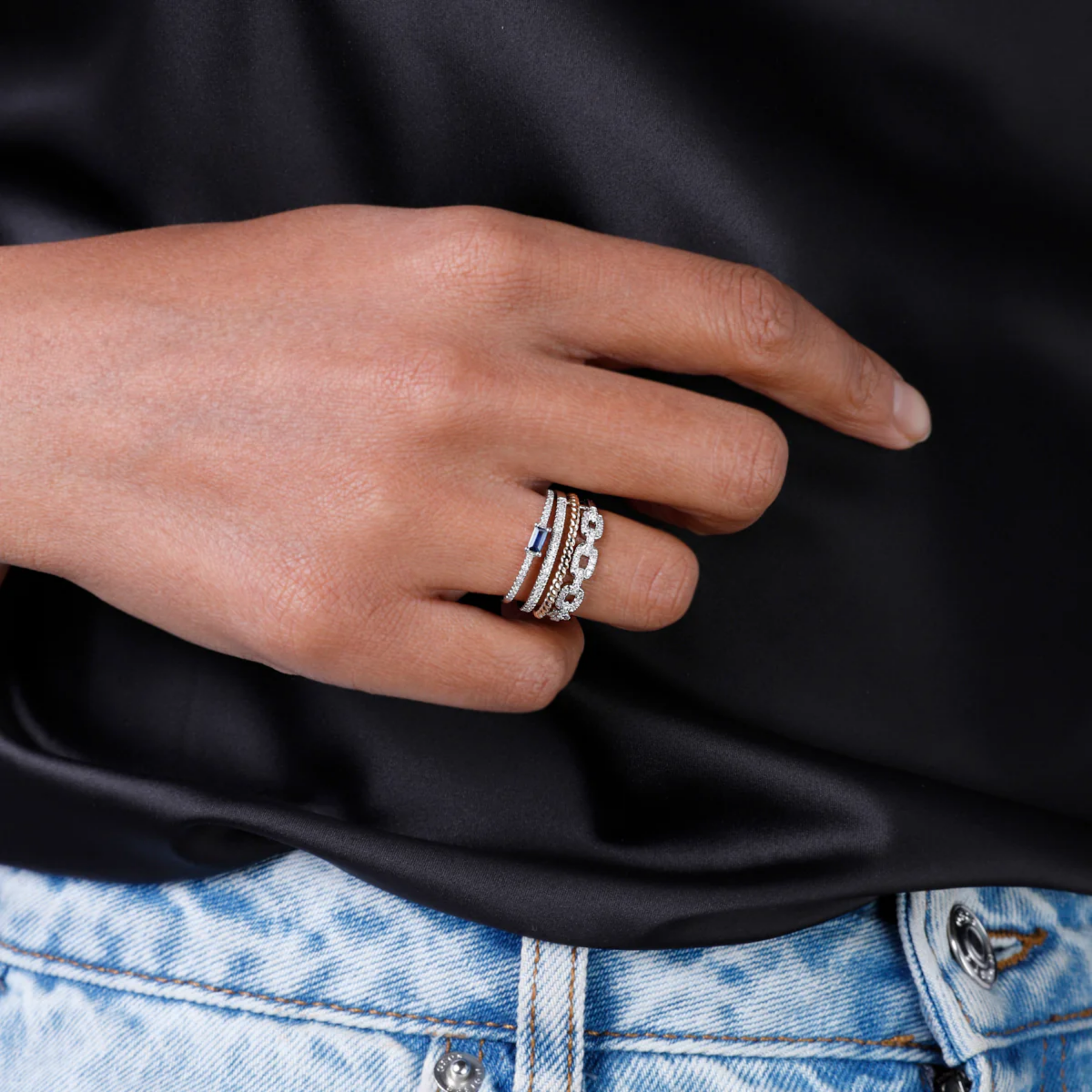 Hand wearing multiple rings with a black background