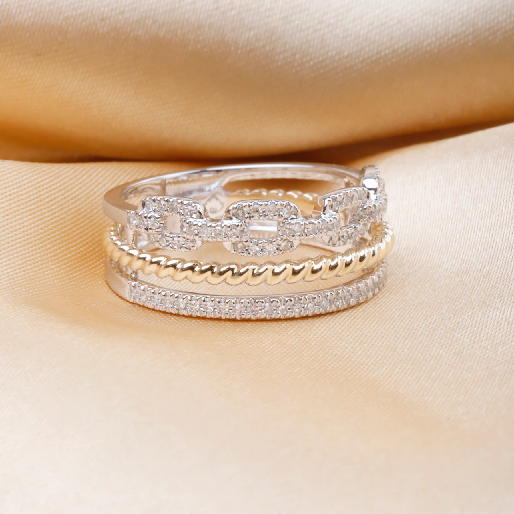 Three gold and silver rings stacked on a beige fabric background