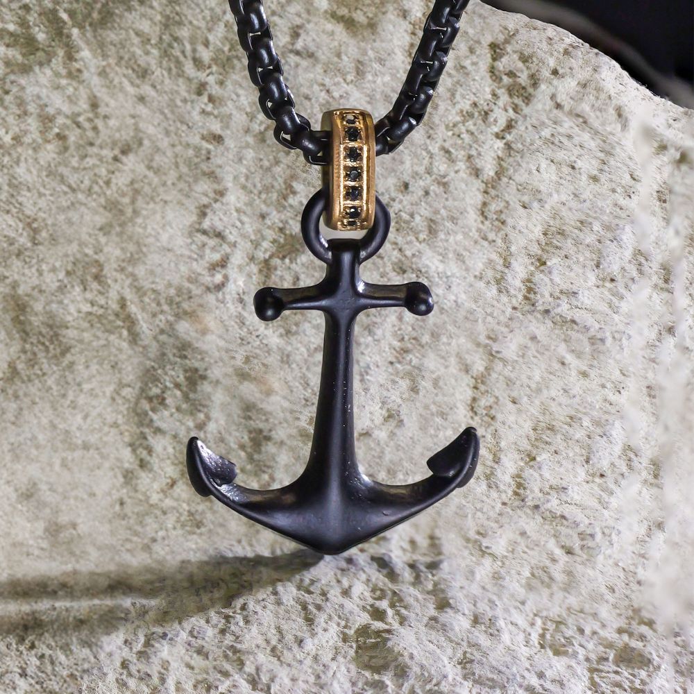 Black IP-Plated Steel Matte Finish Kraken Anchor Pendant Necklace with Golden Glint & Black Sapphire Accented Bail in front of a rock