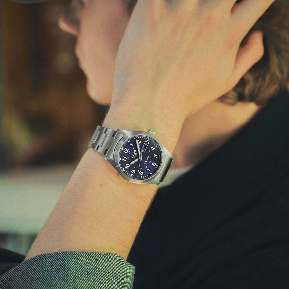SEIKO SRPG29 stainless steel automatic field watch worn on a wrist, showing its blue dial and day-date display.