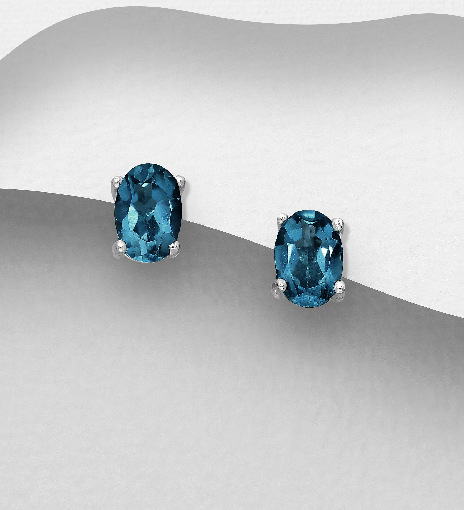 A pair of sterling silver London Blue Topaz oval solitaire stud earrings, displayed against a grey background.