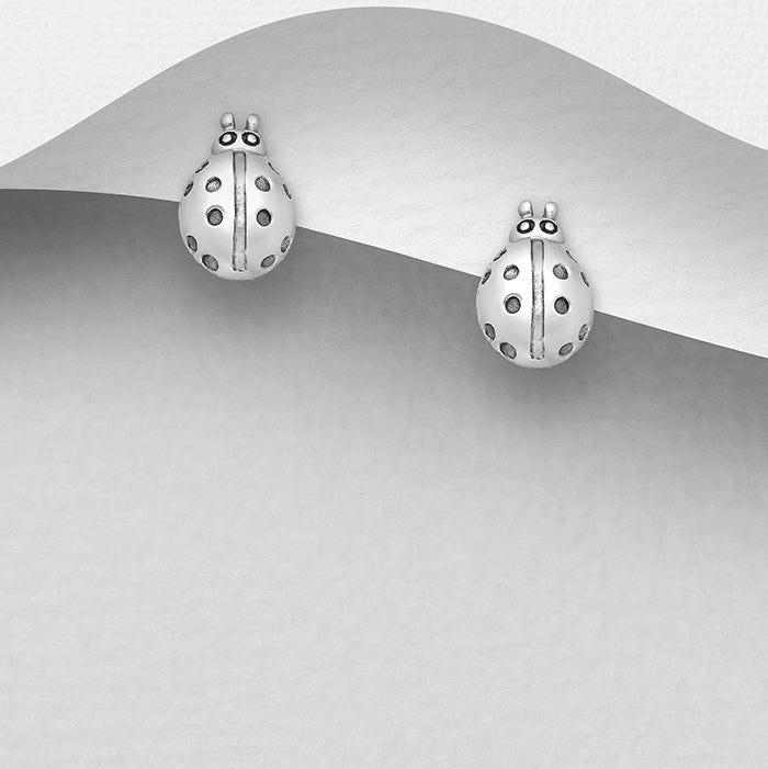 A pair of sterling silver ladybug stud earrings displayed against a grey background.