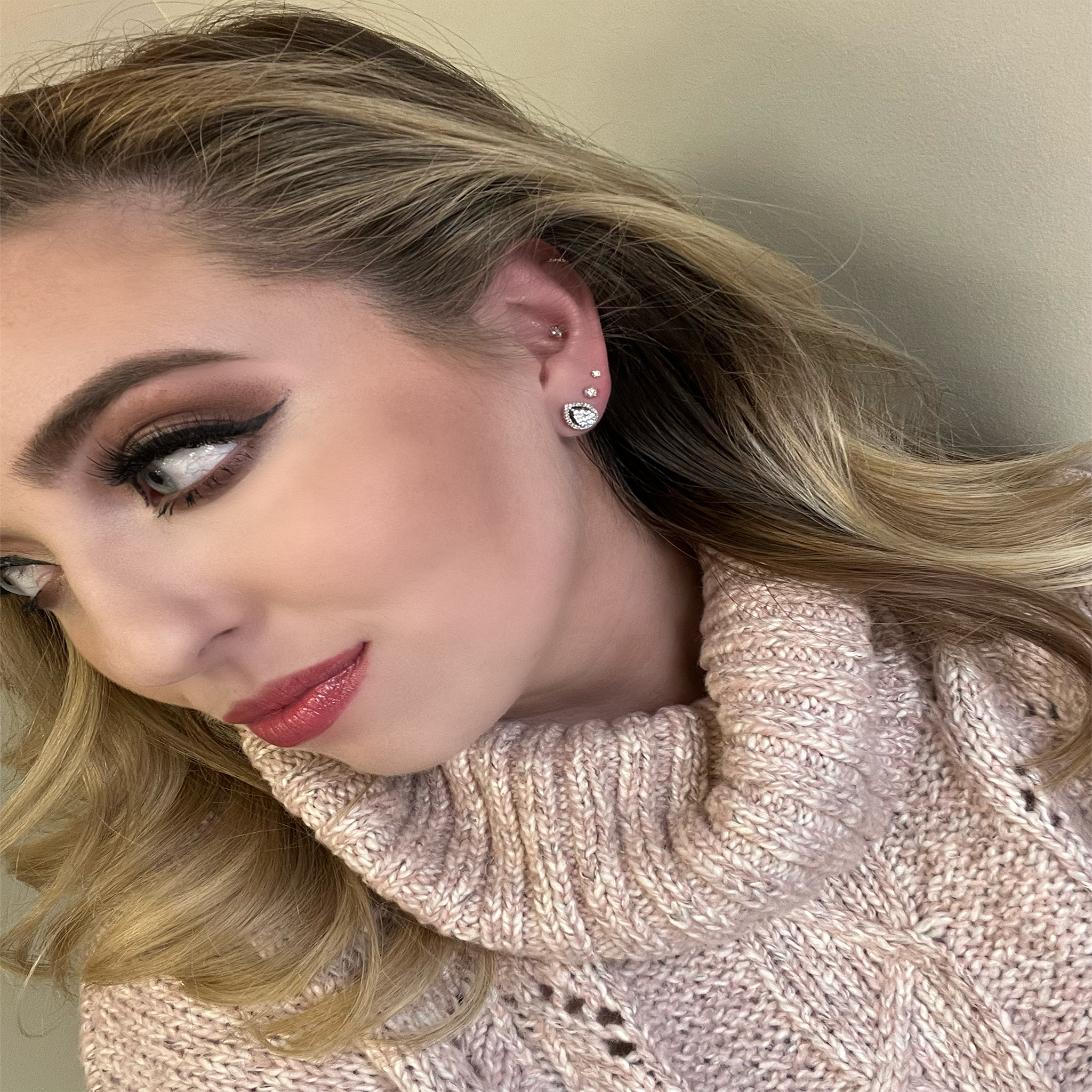10K White Gold 1/2CT. Pear Cluster Halo Stud Earrings on a blonde model wearing a sweater and pink lipstick.