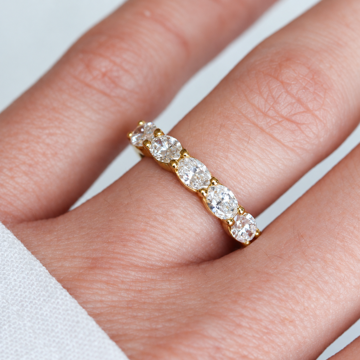 Top view on a hand of the 14K yellow gold five-stone band with 1.25CTW. east-west oval lab-grown diamonds, SKU 130107.