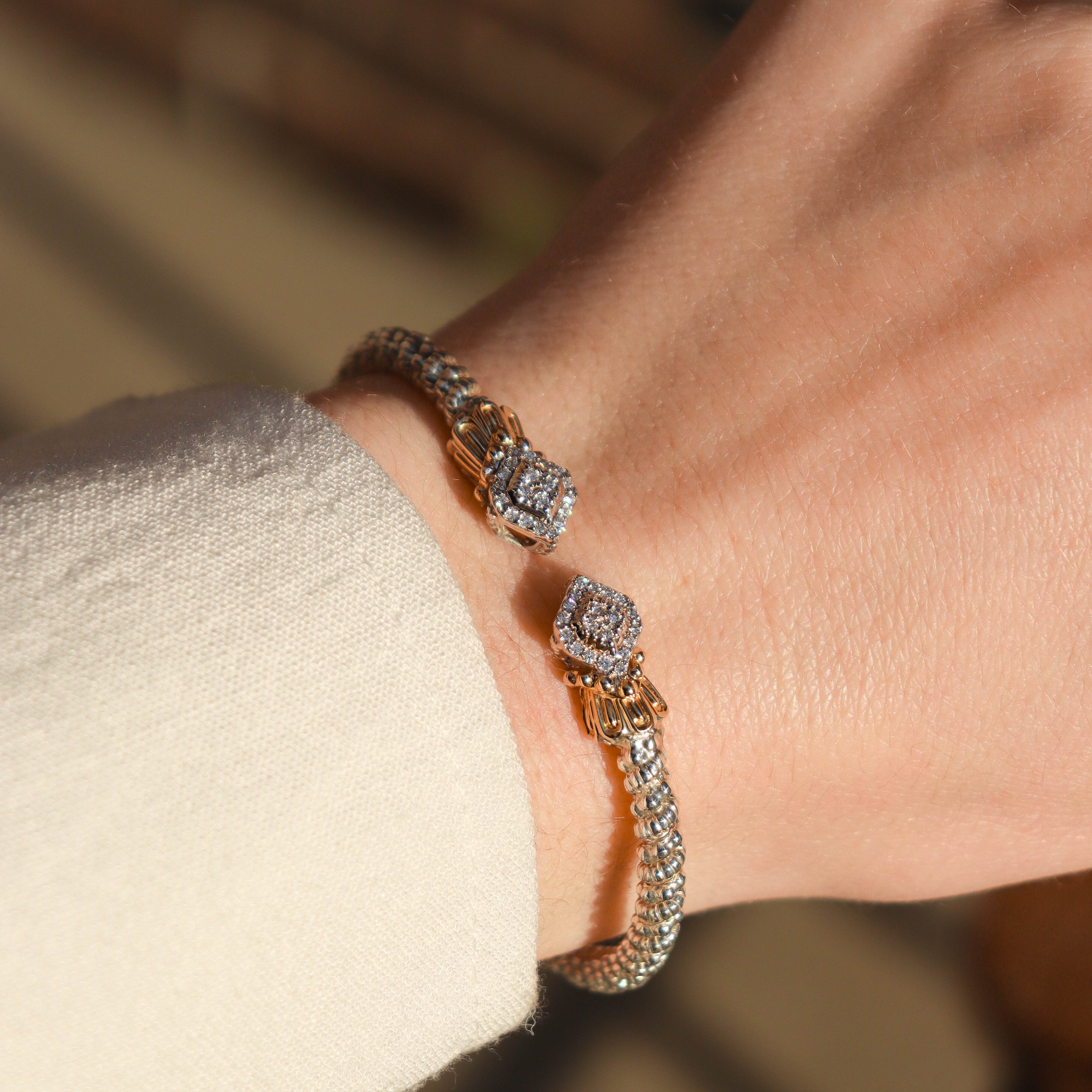 Alwand Vahan Designer Diamond open cuff bangle bracelet on a wrist in front of neutral background.