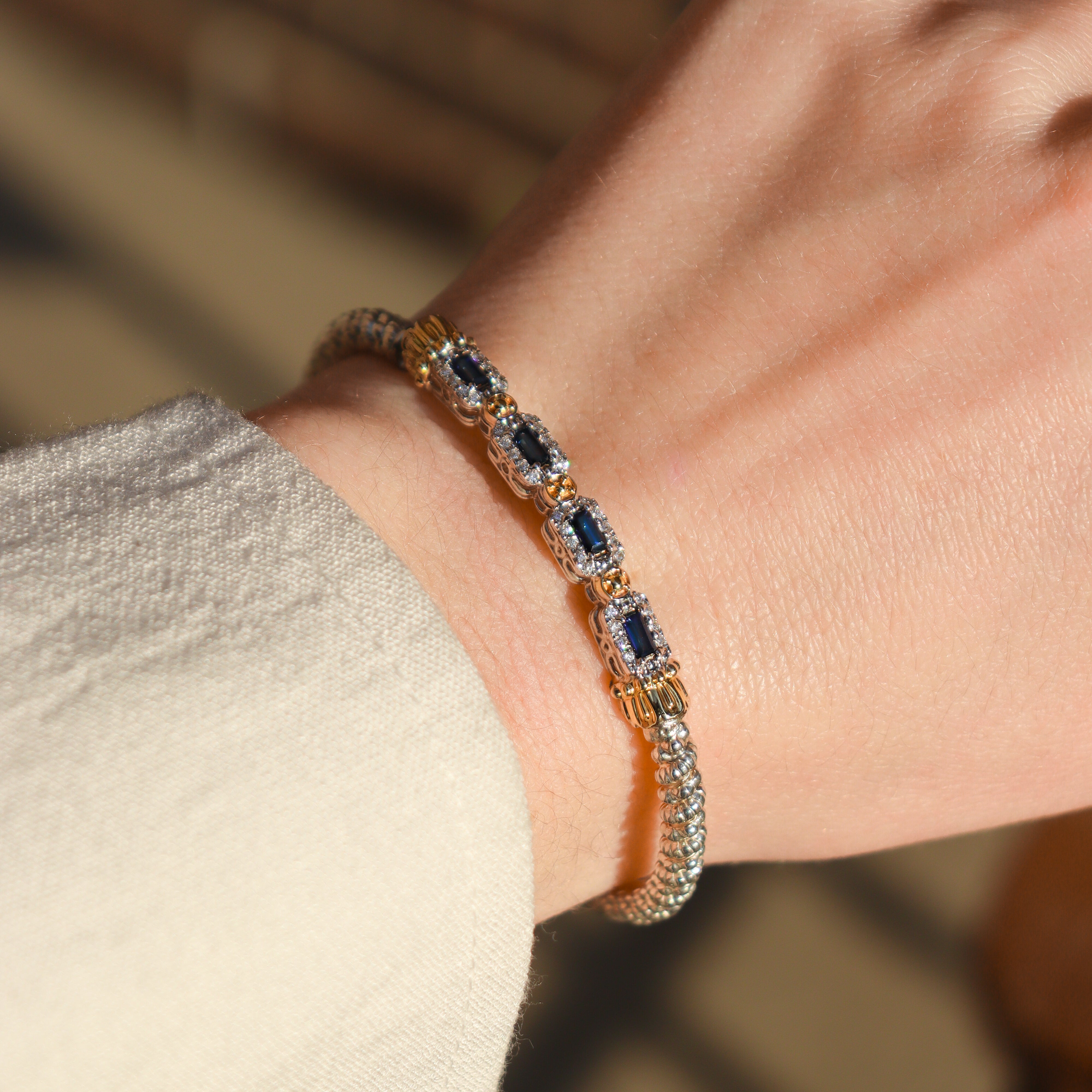 Designer Alwand Vahan Sapphire and Diamond Bracelet on a wrist in front of a blurred neutral background.
