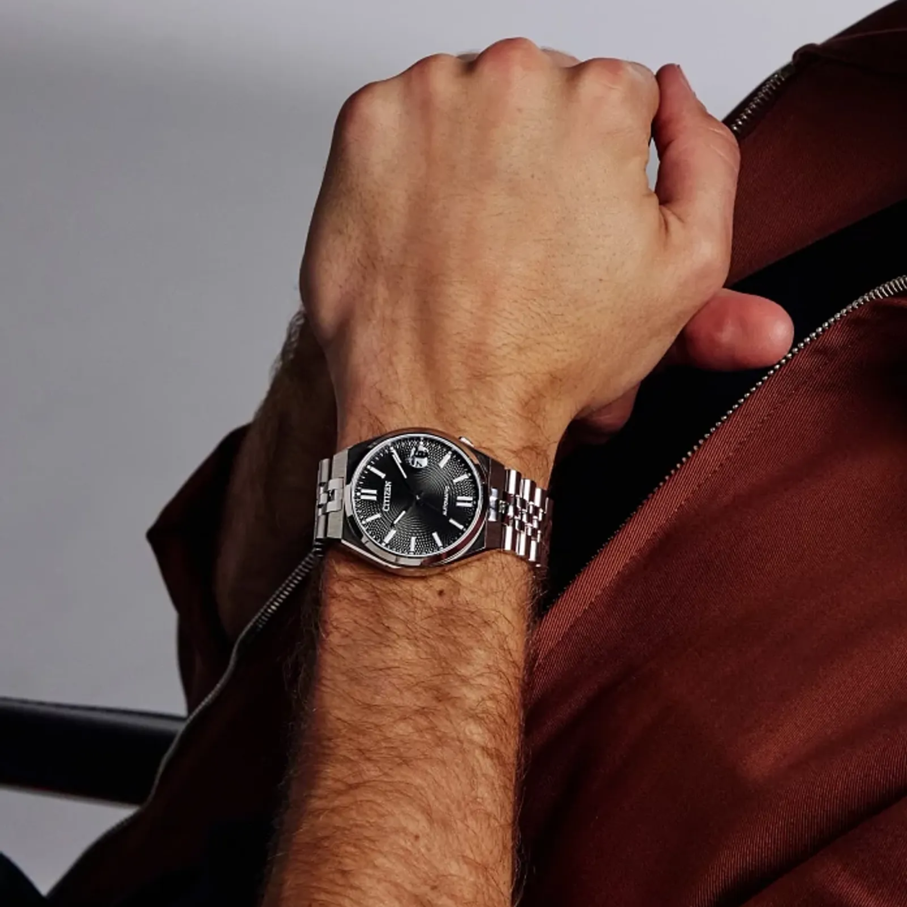 Hand wearing a watch with a blurred background