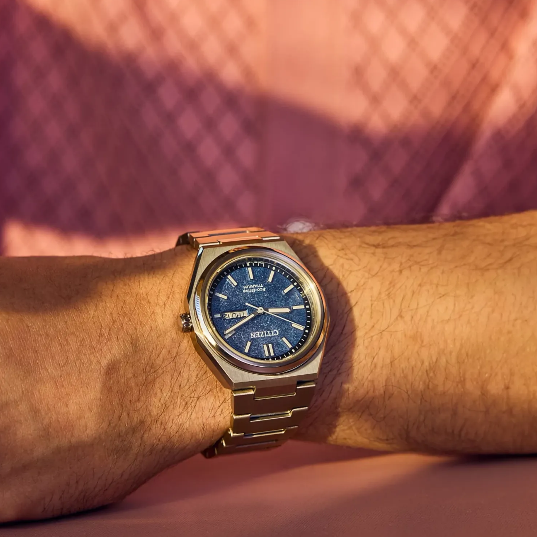 Gold watch with blue face on a wrist against a blurred background