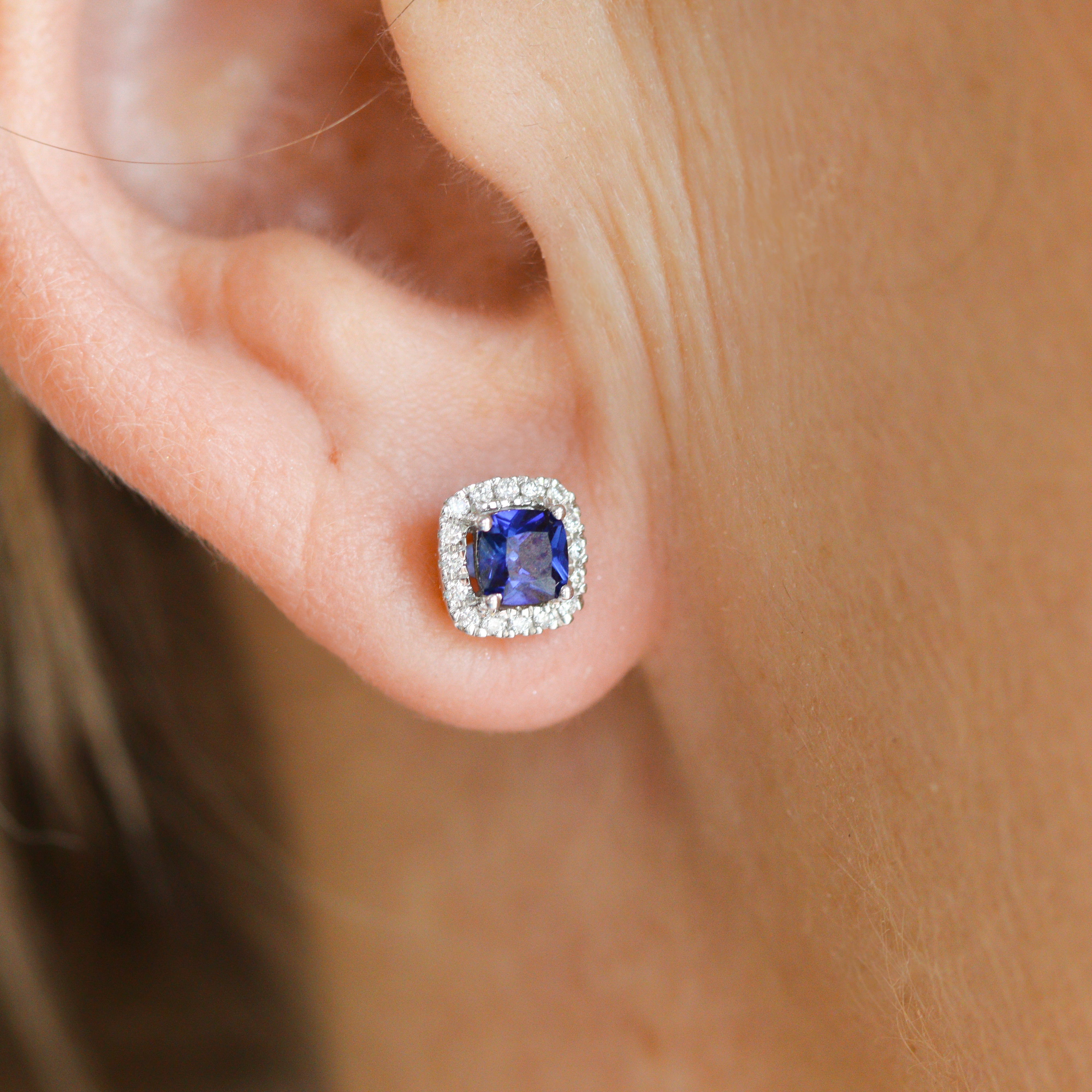 Closeup of one 10K White Gold Created Sapphire & Lab-Grown Diamond Halo Earrings on a model's ear.