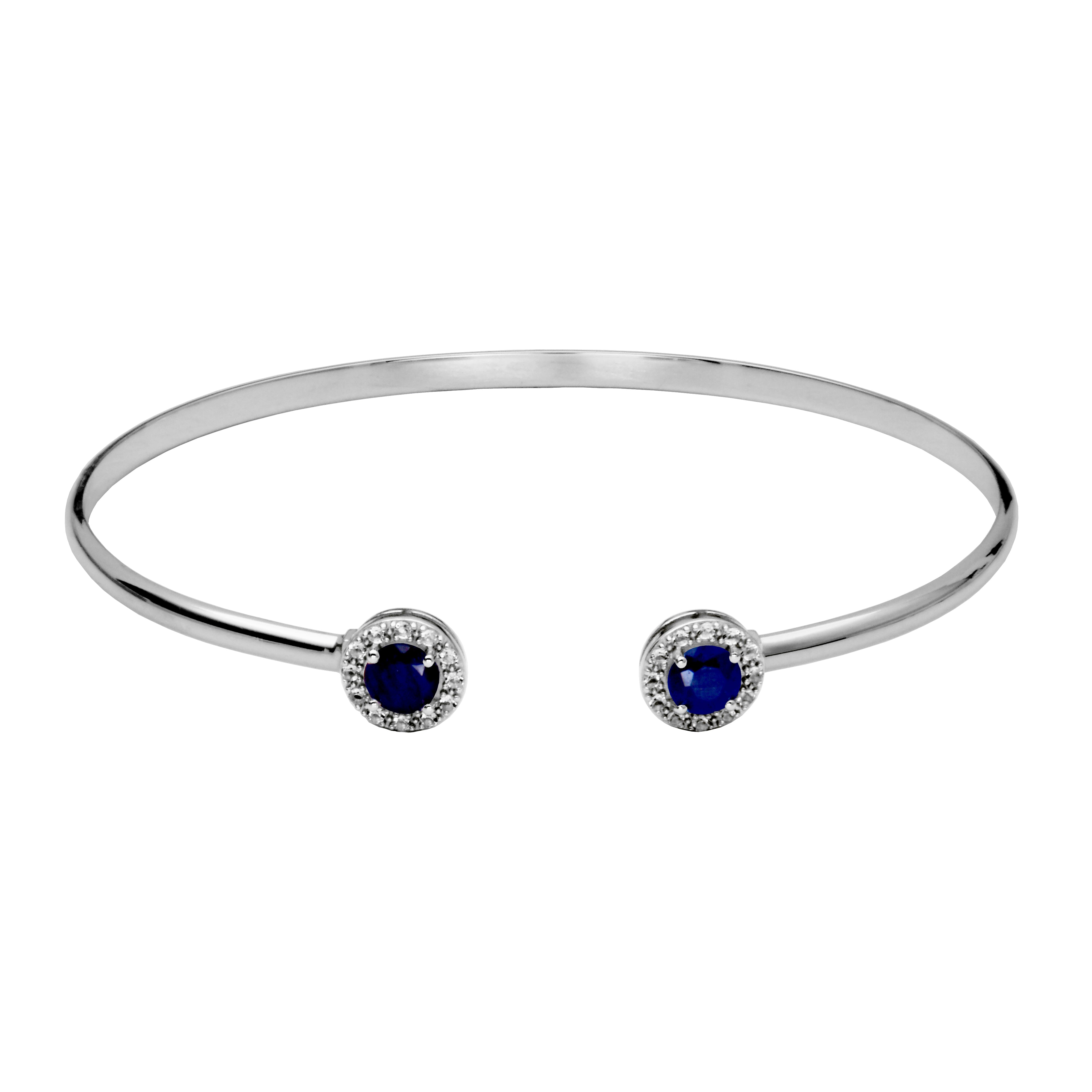 Silver Cuff Bangle Bracelet. On each end of the cuff is a round sapphire surrounded by a halo of whtie topaz gemstones.