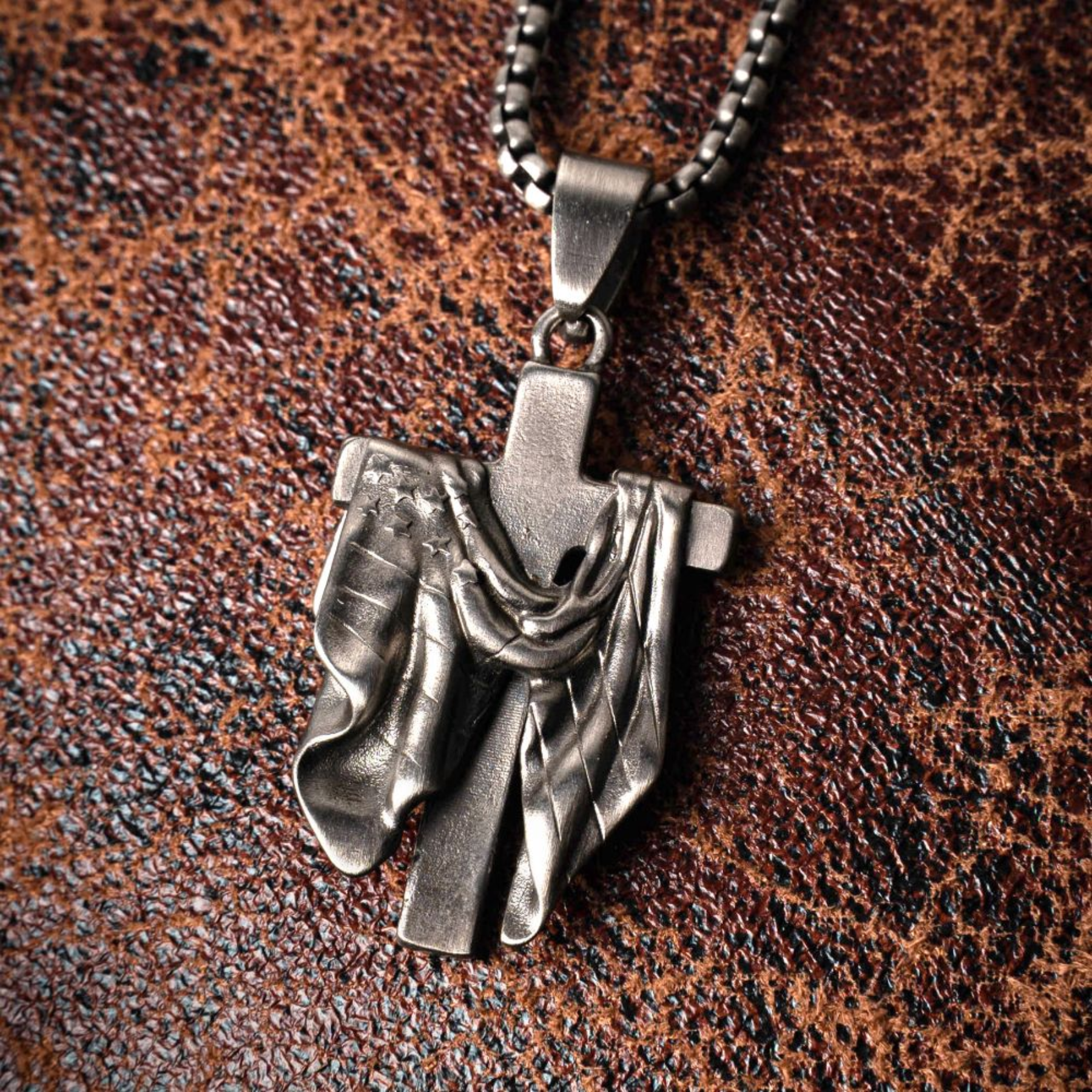 Silver cross pendant necklace on a brown leather background