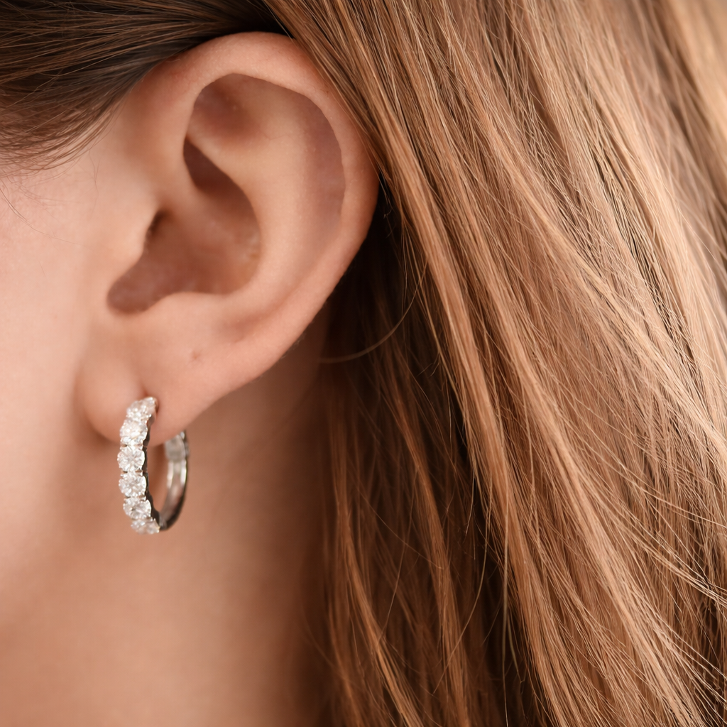 Close-up of an ear wearing a diamond hoop earring with blonde hair.