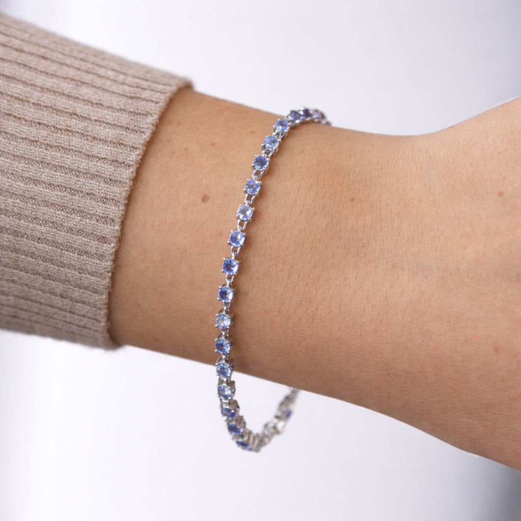Bracelet with blue stones on a wrist against a white background