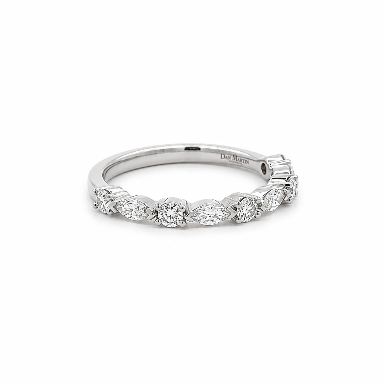 A silver diamond band ring featuring a row of marquise-cut and round diamonds, shown on a clean white background. The inside of the band is engraved with 'DIAMOND MARK'.