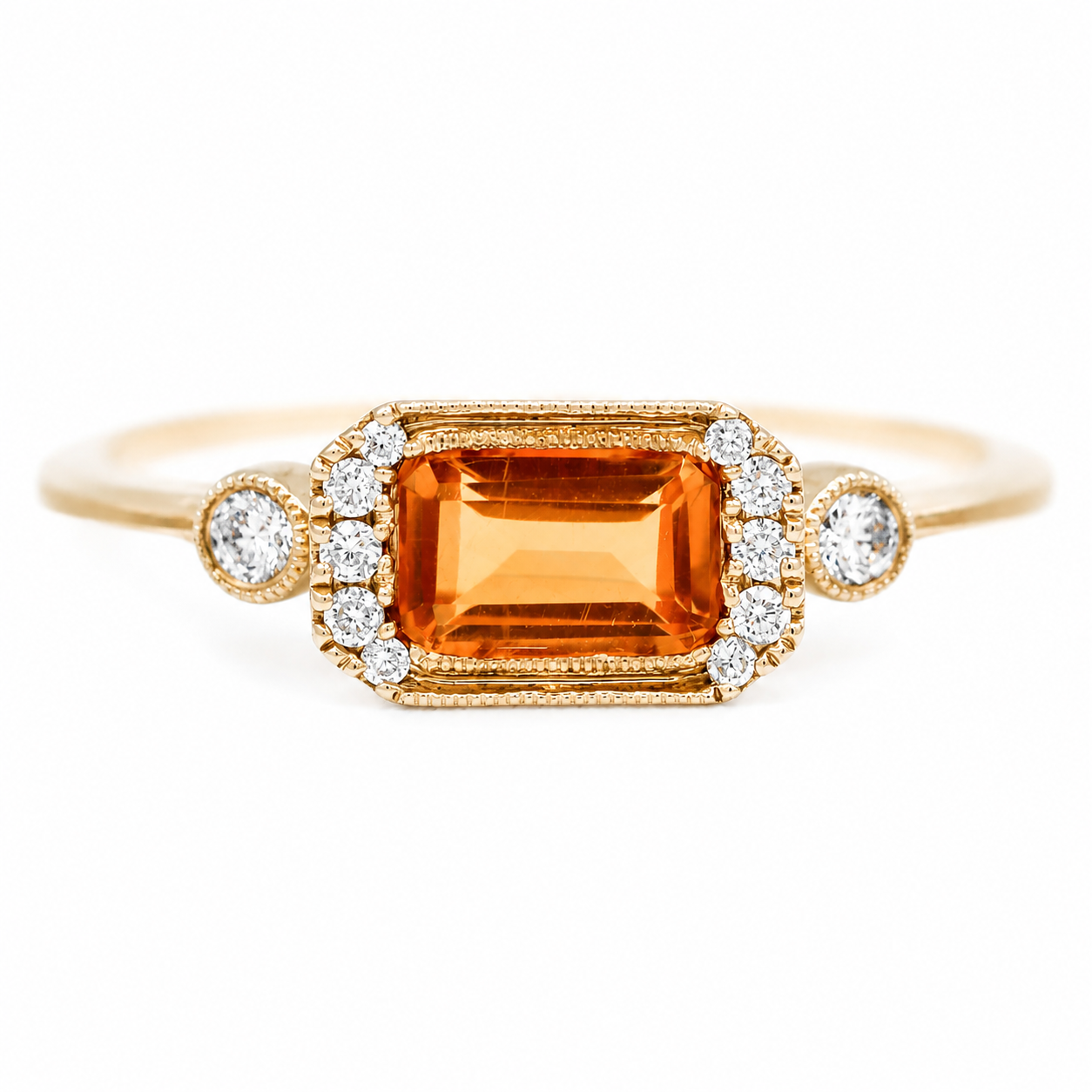 A yellow gold ring featuring a rectangular emerald-cut orange gemstone surrounded by small clear accent diamonds, with two round diamonds on either side of the main stone, set against a plain white background.