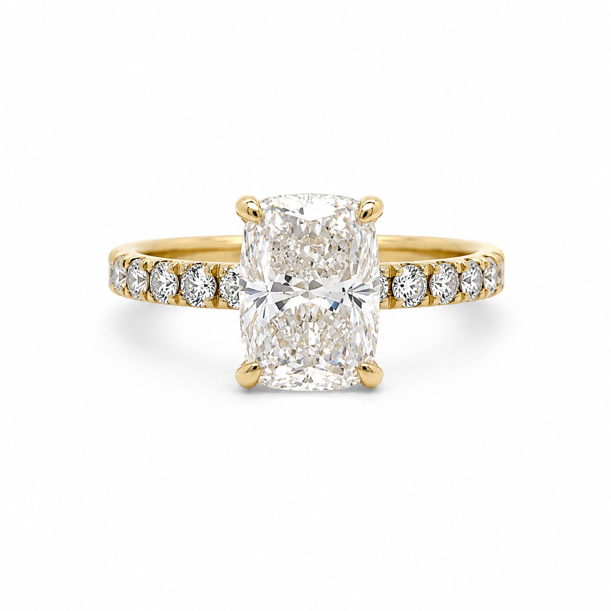 A yellow gold engagement ring featuring a large cushion-cut diamond center stone and smaller diamonds set along the shoulders of the band, shown on a clean white background.