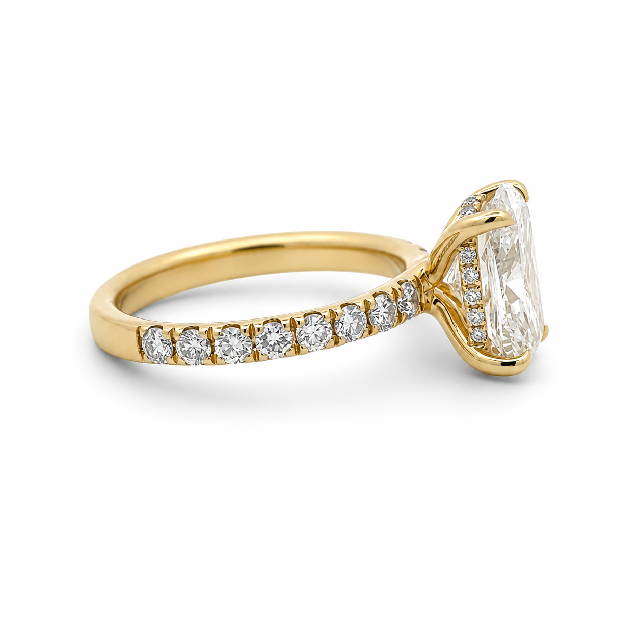 A yellow gold engagement ring featuring a large rectangular clear center stone and a pavé band set with small round diamonds, shown on a clean white background.