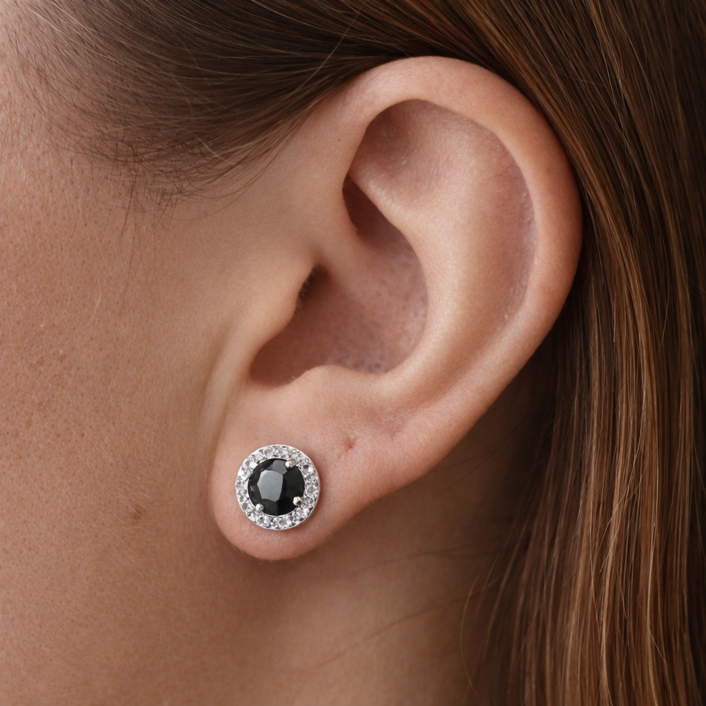 Close-up of an ear wearing a black gemstone earring with a silver setting.