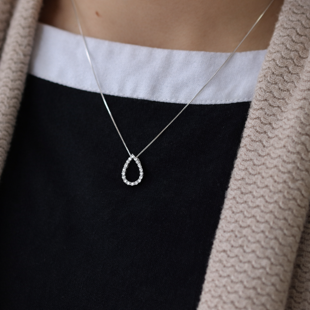 Necklace with a teardrop-shaped pendant worn by a person against a neutral background