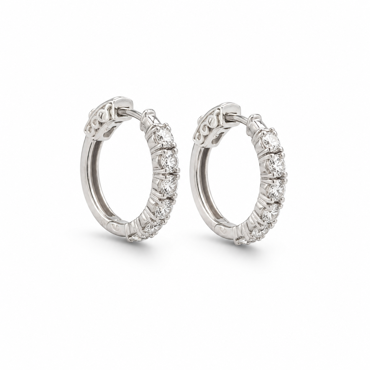 Pair of silver hoop earrings with clear stones on a white background