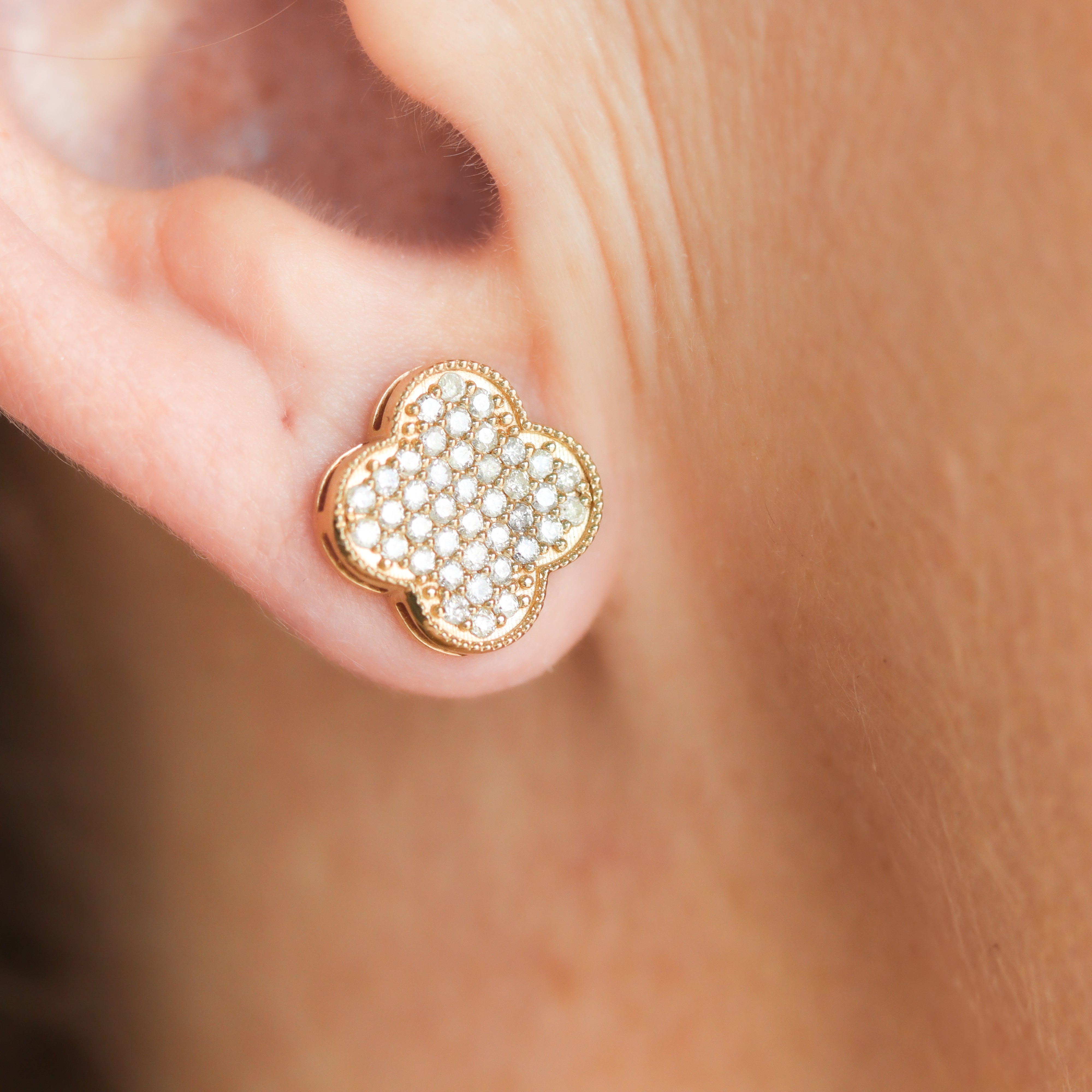 One 14K Yellow Gold 5/8CT. Diamond Clover Stud Earrings on a model's ear close up.